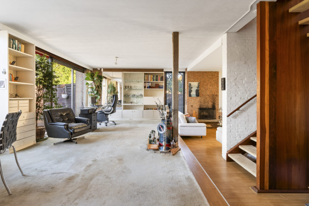 Modern open living room with fireplace and bookshelf.