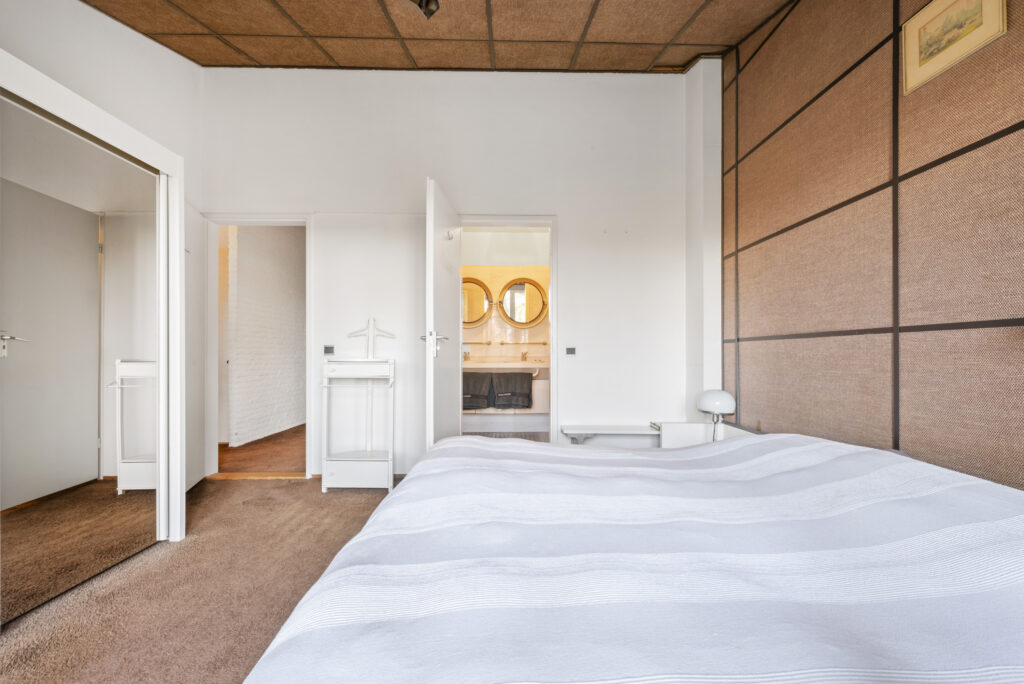 Modern bedroom with open bathroom doors