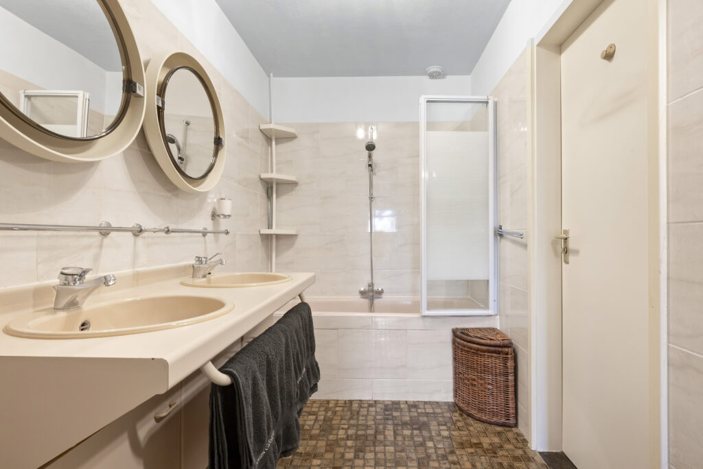 Modern bathroom with double sinks and shower.