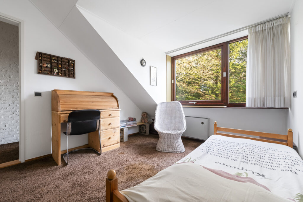 Cozy attic bedroom with desk and brown carpet