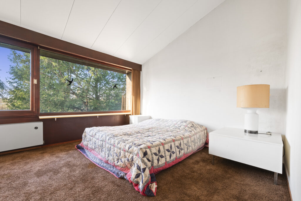 Bedroom with window, bed, nightstand, and lamp.