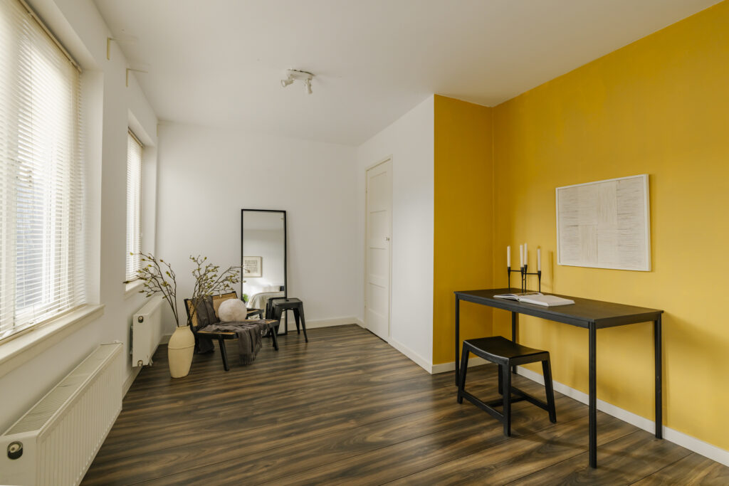 Modern room with yellow accent wall and desk.