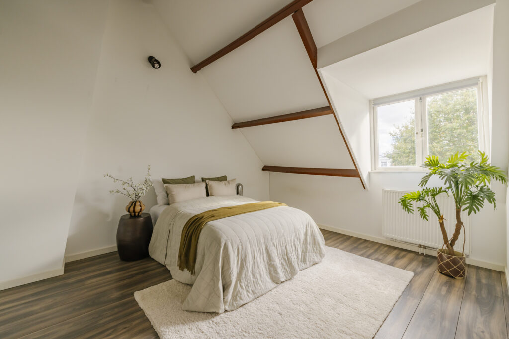 Cozy attic bedroom with plants, wooden beams.