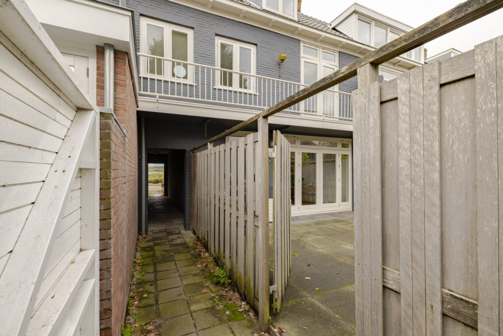 Modern townhouse with patio and wooden fence.