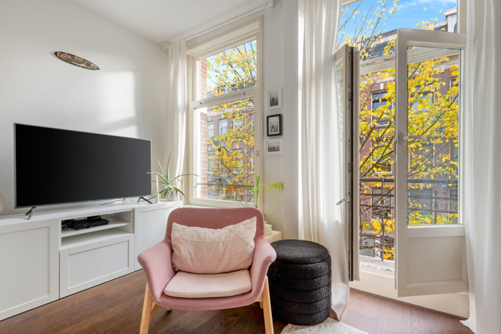 Bright living room with open window and TV