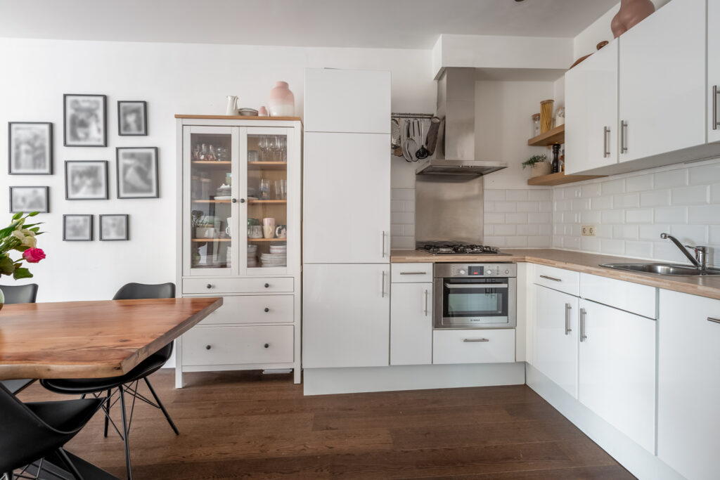 Modern kitchen with white cabinets and wooden dining table.