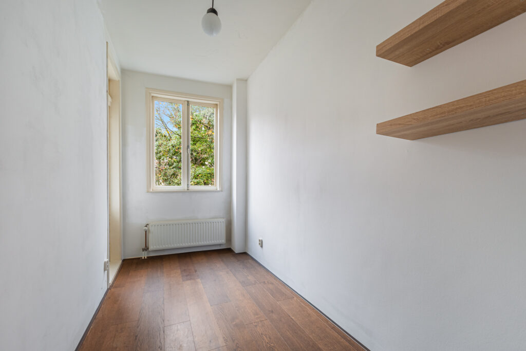 Small empty room with window and shelves.