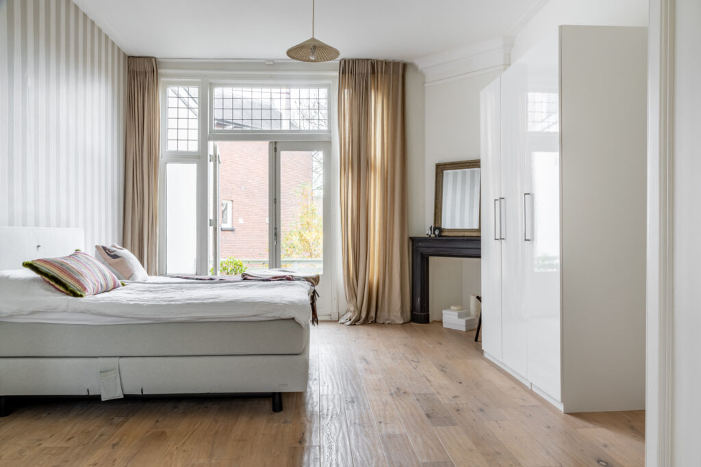 Spacious bedroom with large windows and wood flooring.