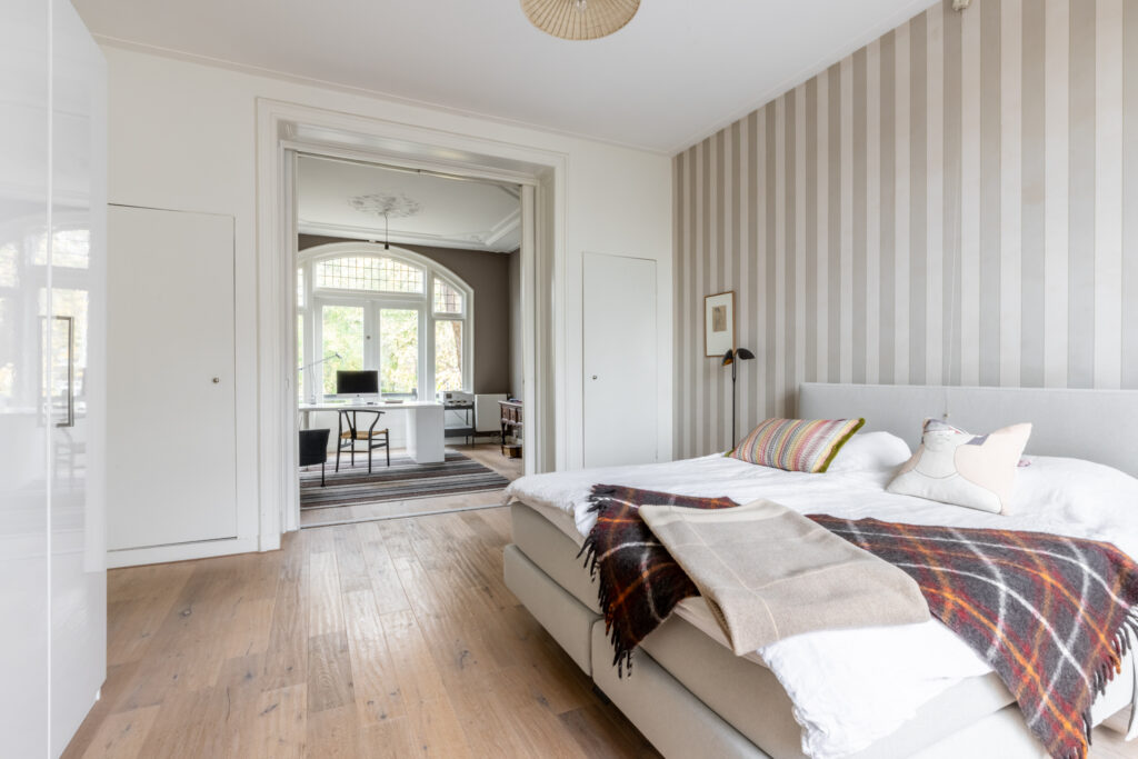 Spacious bedroom with modern office area and decor.