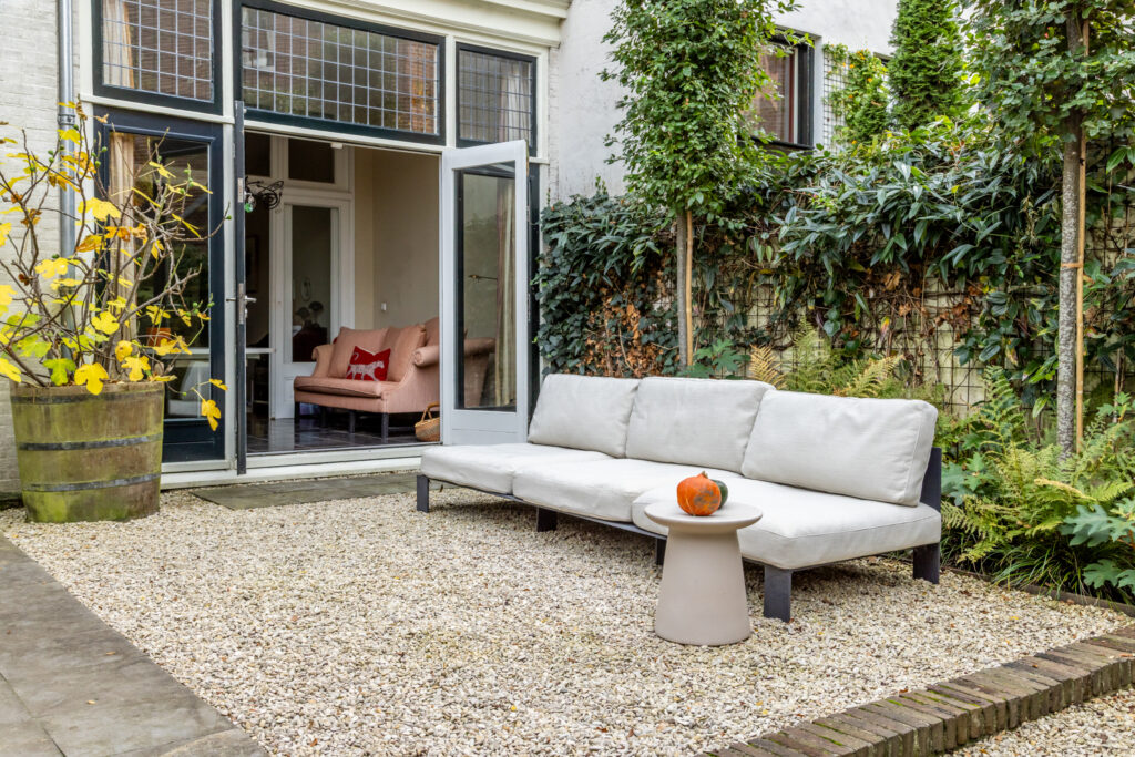 Cozy backyard with sofa and open glass doors.