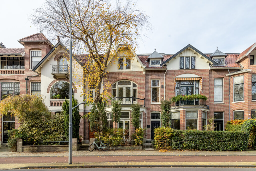 Historic brick townhouse with large windows and trees.