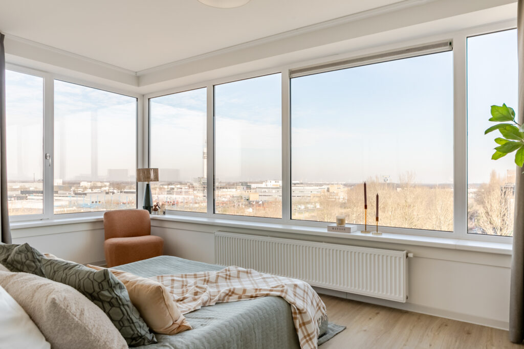 Bright bedroom with large windows and city view.