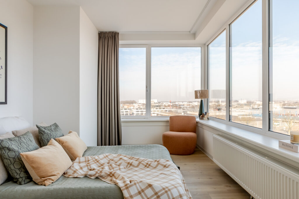 Modern bedroom with large windows and city view.