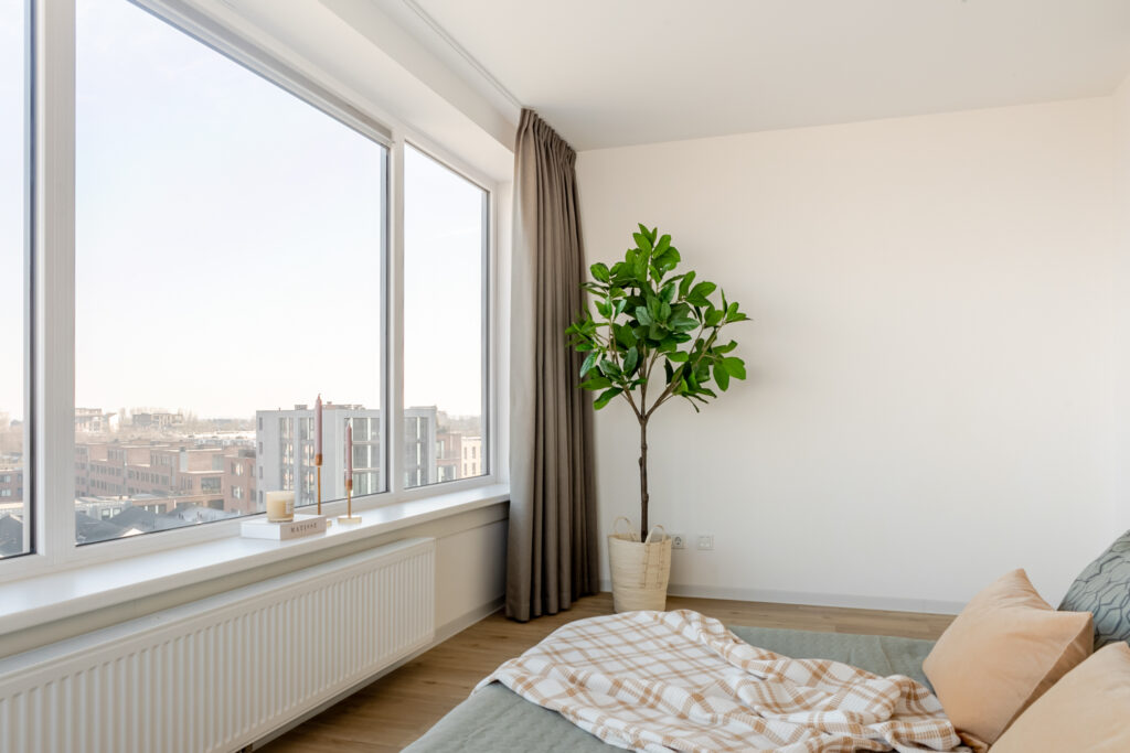 Bright bedroom with large window and potted plant.