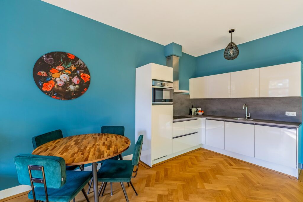 Modern kitchen with teal walls and dining area.
