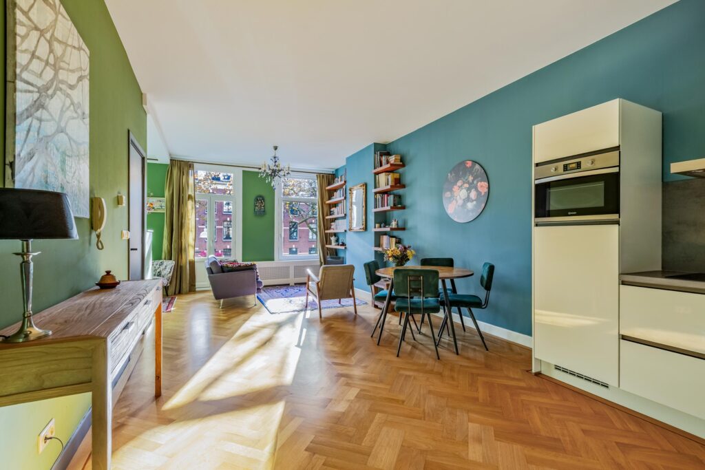 Modern living room with teal walls and wooden floors.