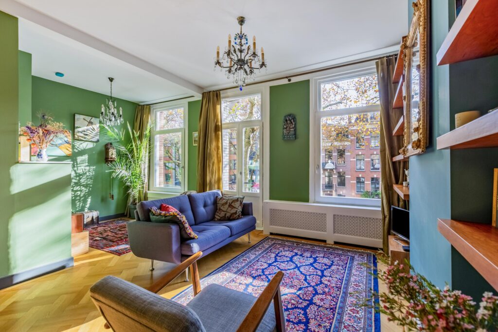 Cozy living room with green walls and large windows.