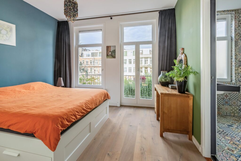 Bright bedroom with orange bedding and green accents.