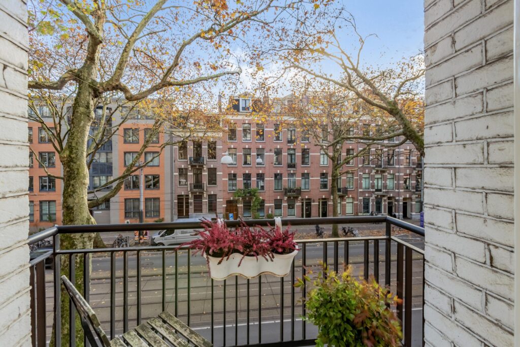 Balcony view of street and buildings with autumn trees.