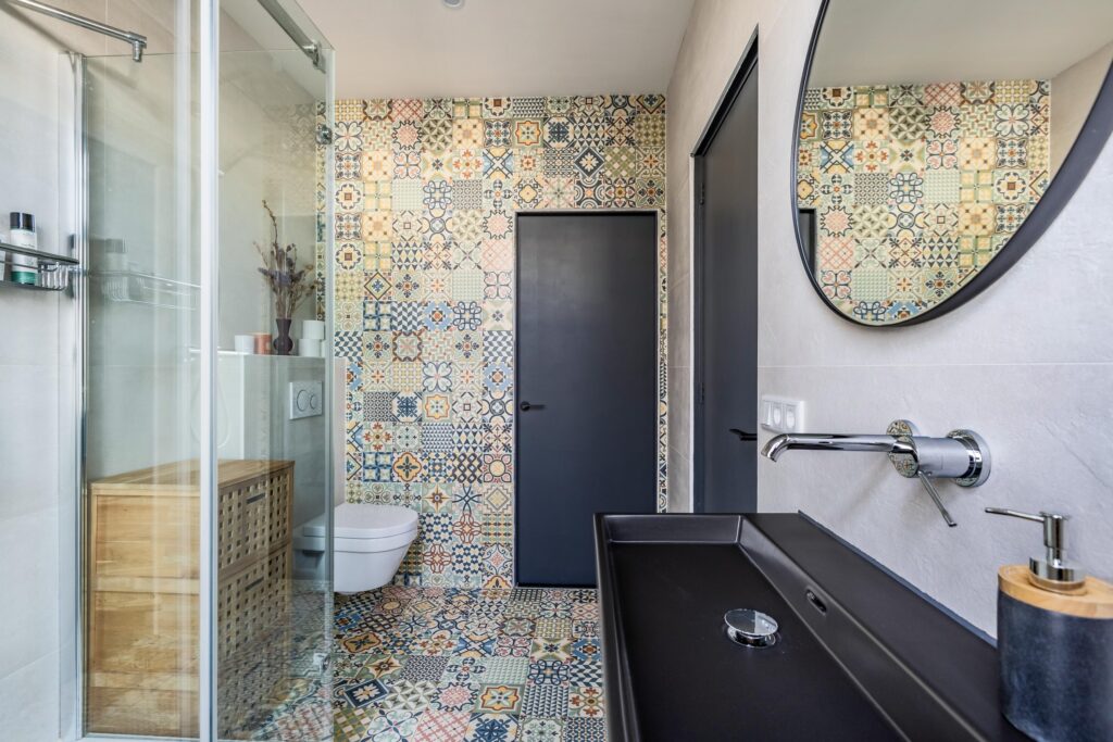Colorful tiled bathroom with modern fixtures and mirror.