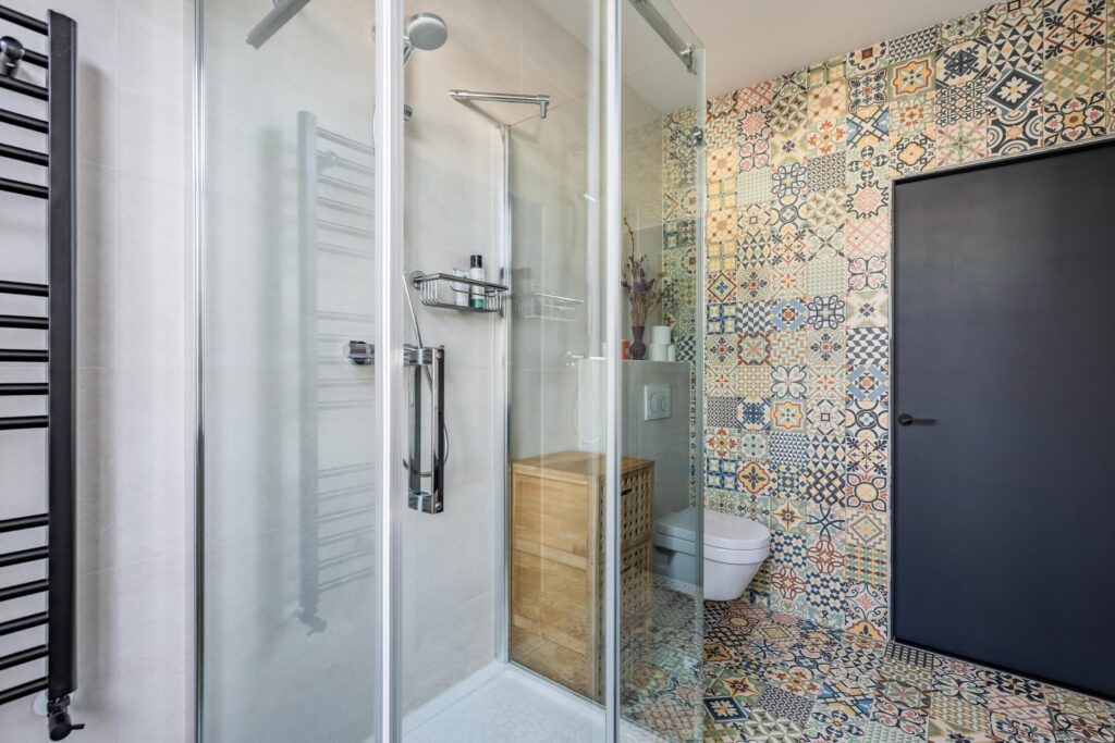 Colorful tiled bathroom with glass shower door.