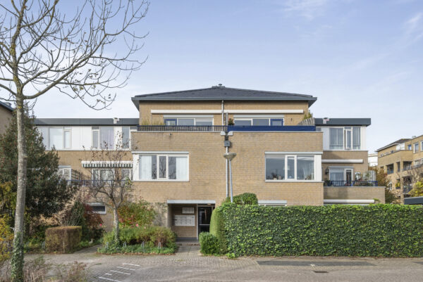 Modern brick apartment building with greenery.