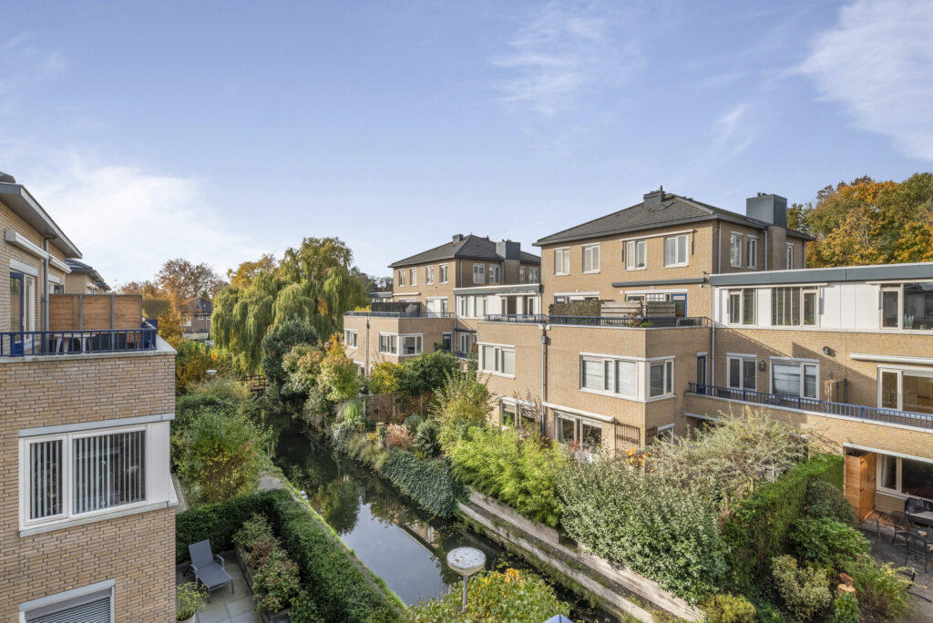 Townhouses beside a canal with greenery.