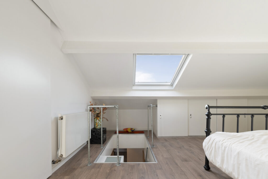 Cozy attic bedroom with skylight and wooden floor.