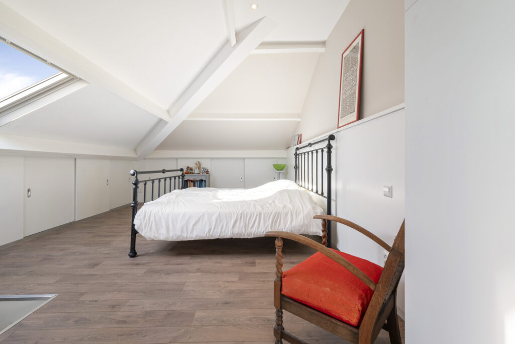 Cozy attic bedroom with skylight and wooden floors.