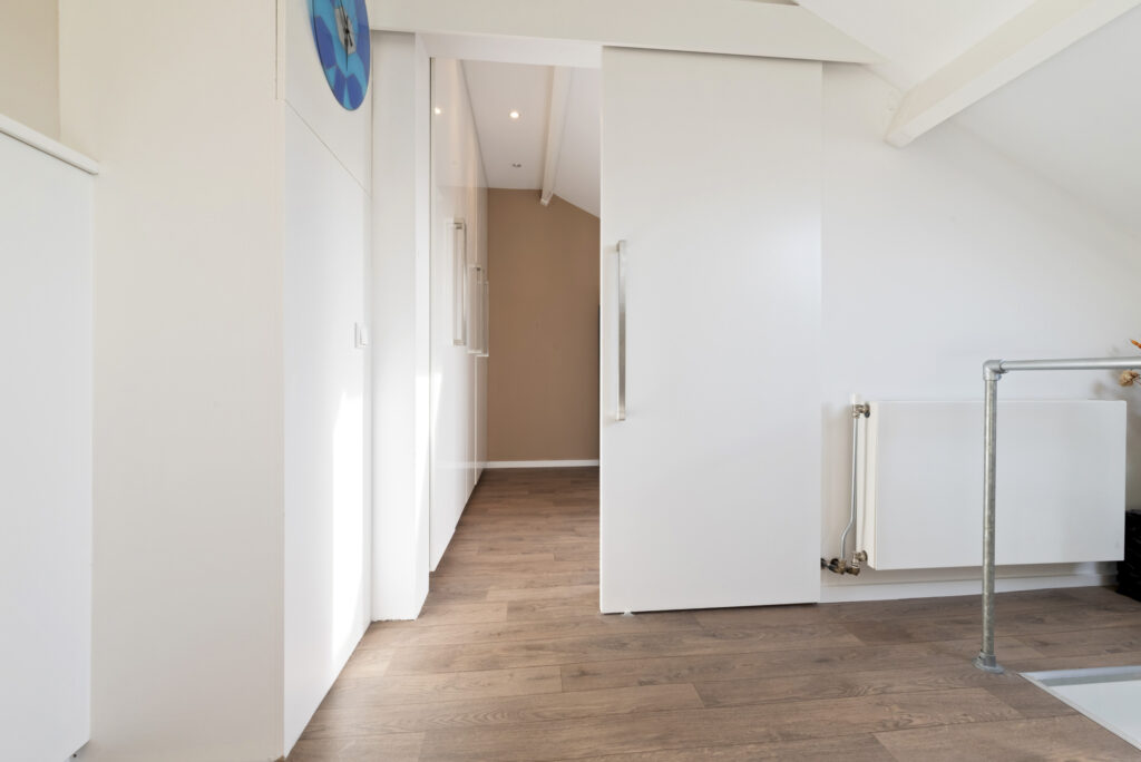 Bright hallway with wooden floor and white walls.
