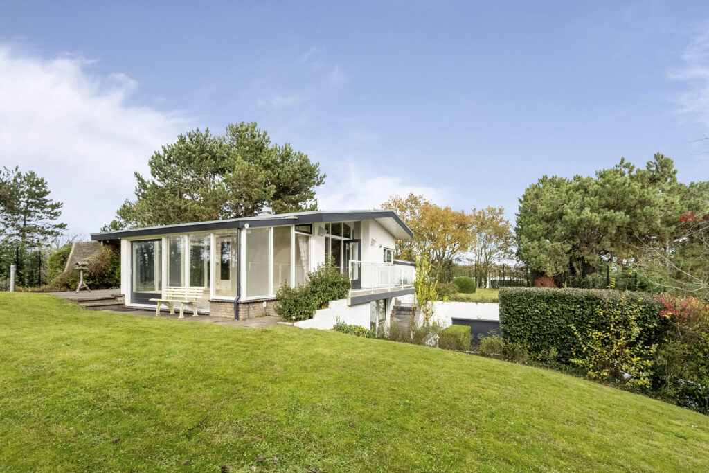 Modern house with large windows and garden view.