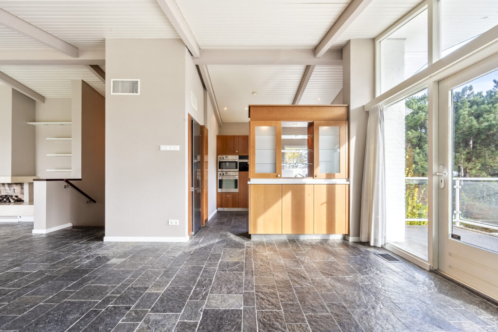 Modern kitchen with large windows and tile floor.