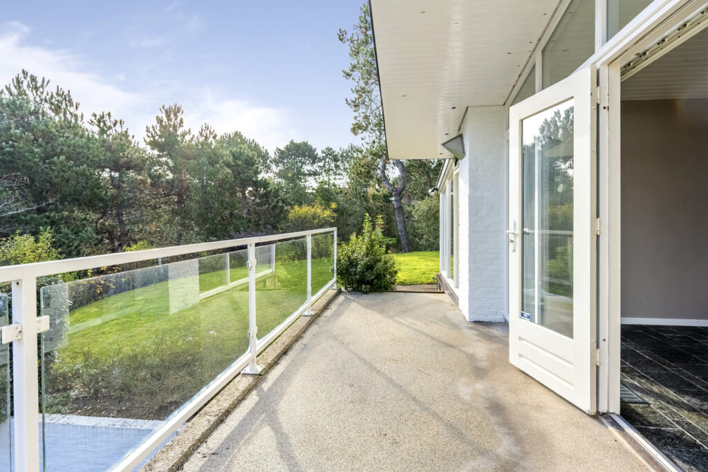 Open patio door with view of garden and trees.
