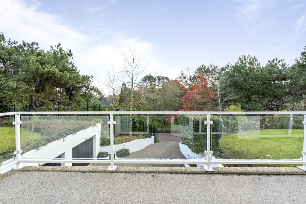 Scenic view from balcony overlooking garden with trees.