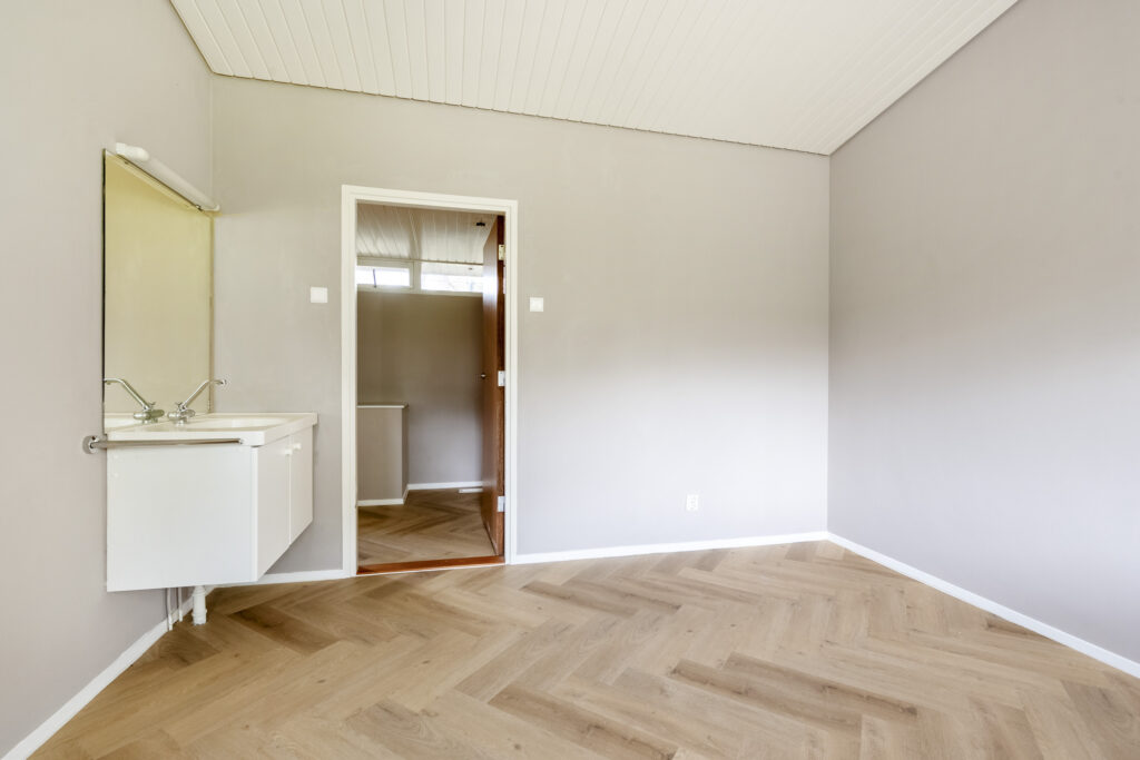 Empty room with sink and wooden floor.