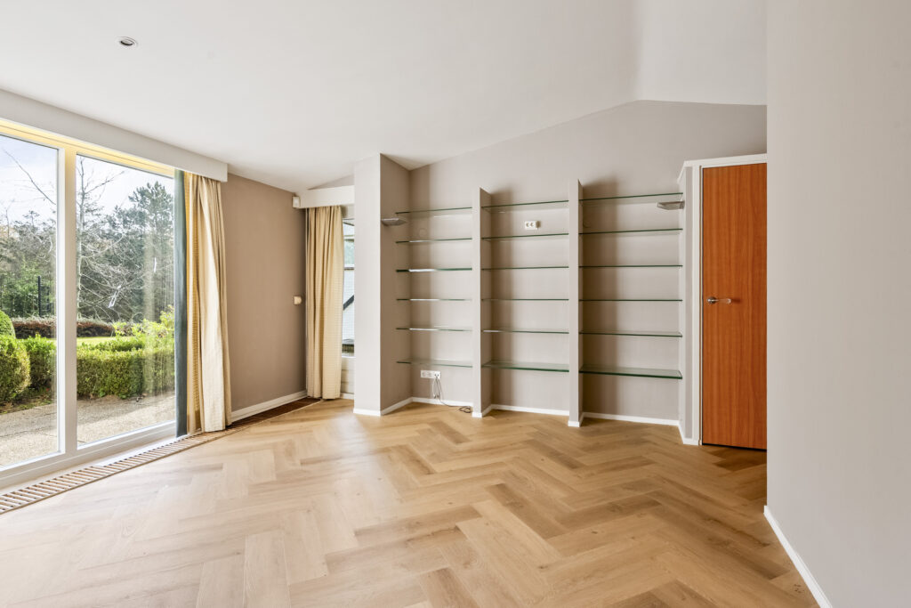 Vacant room with wooden floor and large windows.