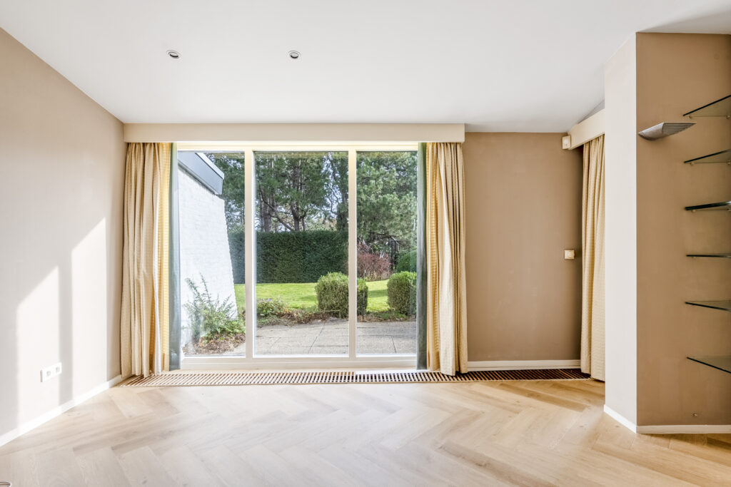 Empty room with large window and garden view.