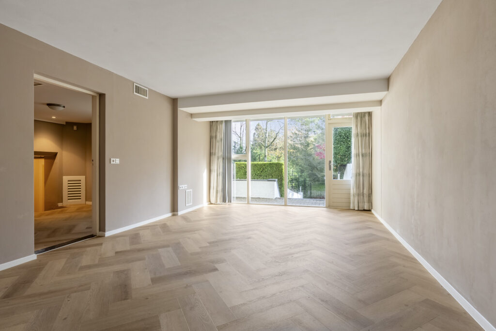 Spacious empty room with wooden floor and large window.