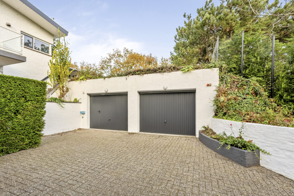 Twin garage doors with surrounding greenery.
