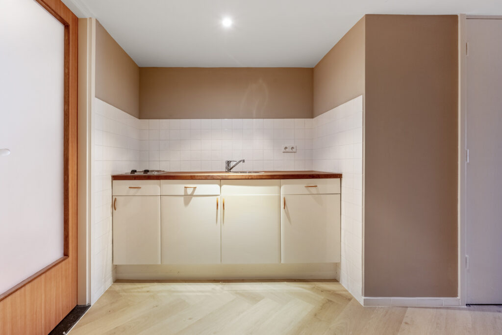 Small kitchen with beige cabinets and wood counter.