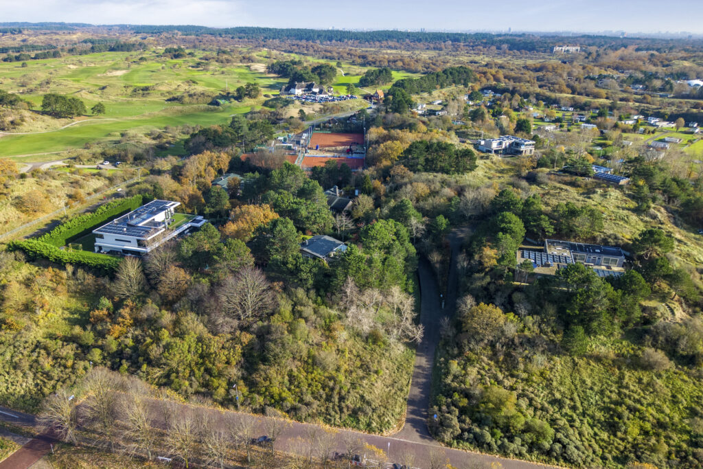 Aerial view of lush landscape with tennis courts.