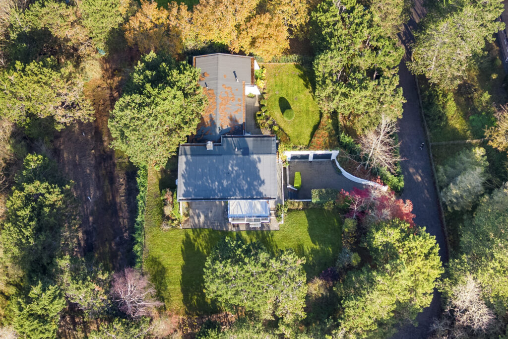 Aerial view of house surrounded by trees in autumn.