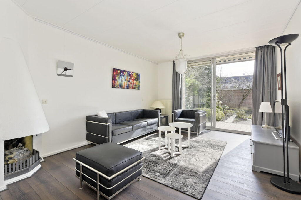Modern living room with black furniture and large windows.
