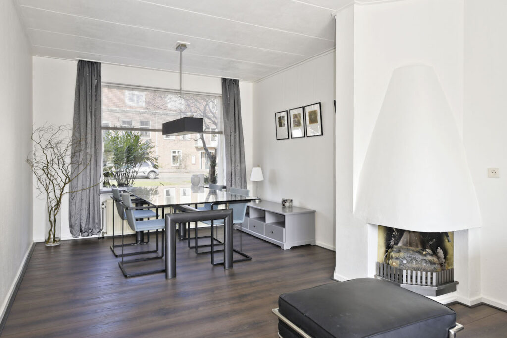 Modern dining room with glass table and fireplace.