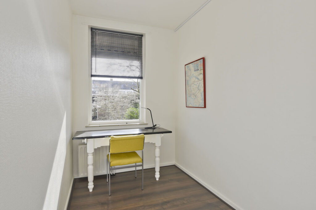 Minimalist office with desk, chair, and window view.