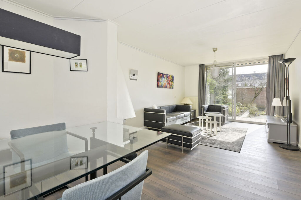 Modern living room with glass table and black couches.