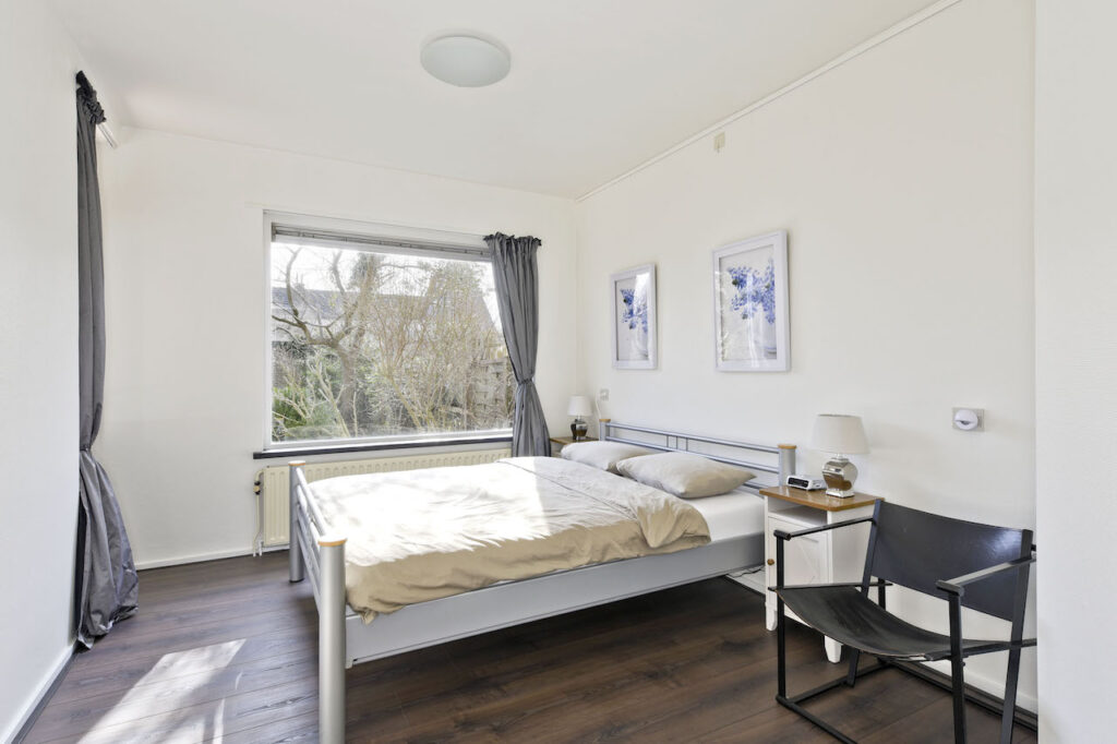 Bright bedroom with double bed and large window.