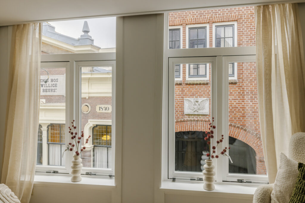View of historic buildings through large windows with vases.