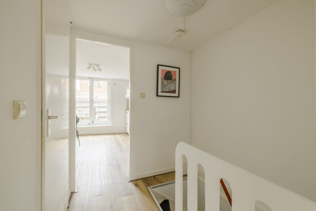 Bright hallway with staircase and artwork on wall.