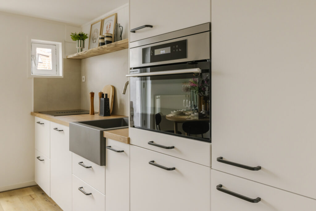Modern kitchen with white cabinets and built-in oven.